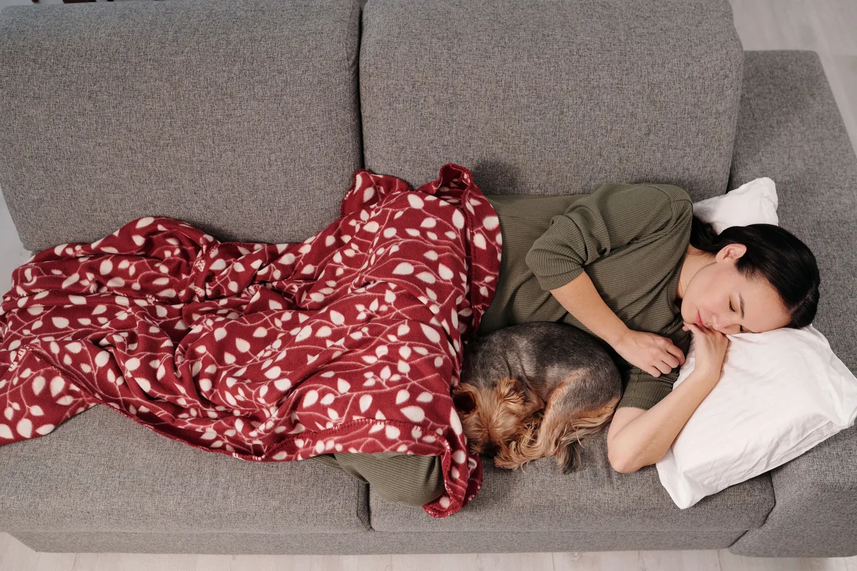 A person resting on a sofa with a dog